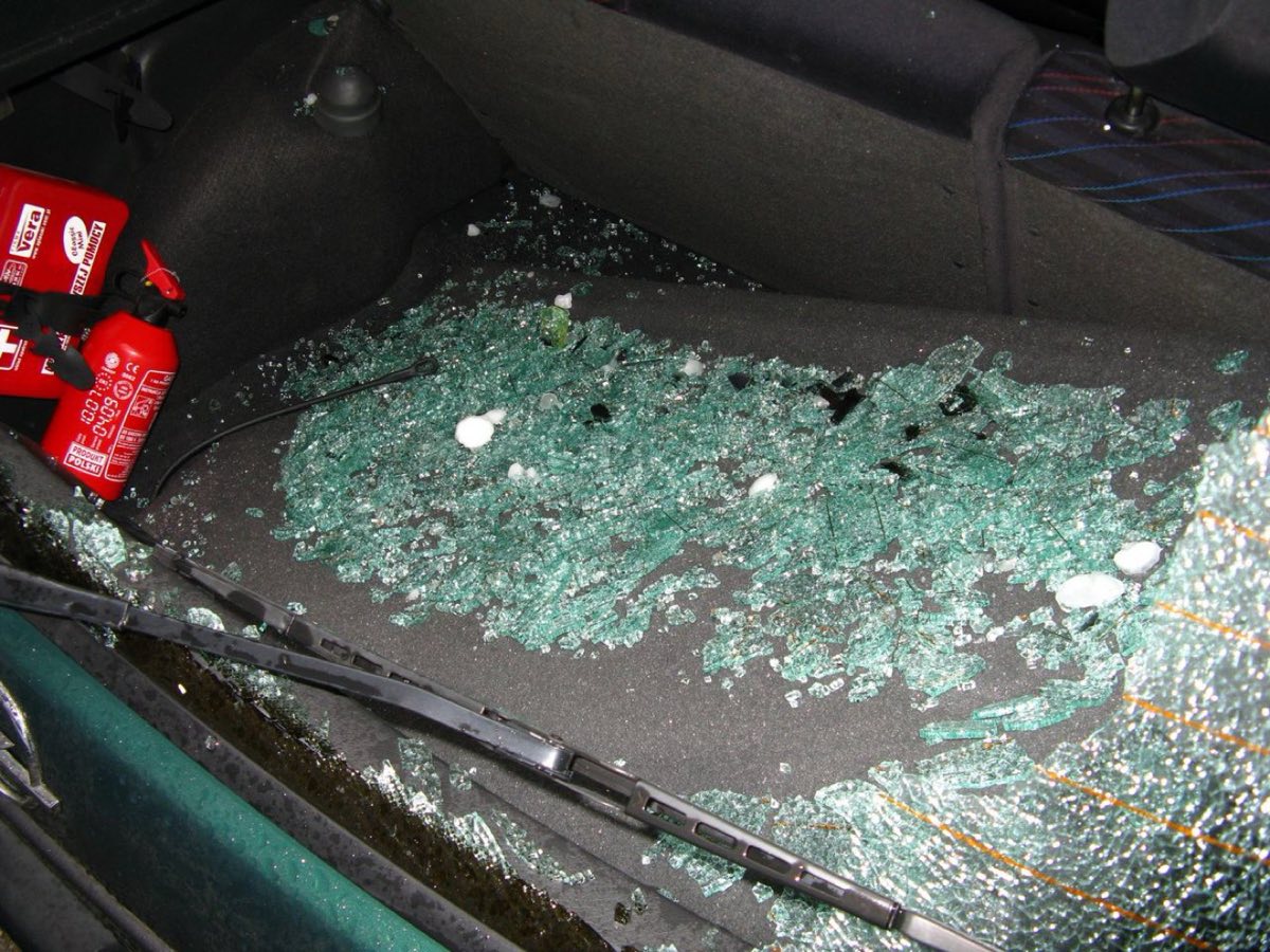 Achterruit van een auto volledig verbrijzeld door grote hagelstenen