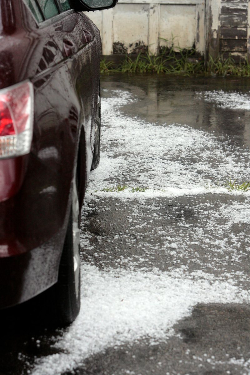 Auto geparkeerd op een oprit met een dikke laag hagel eromheen
