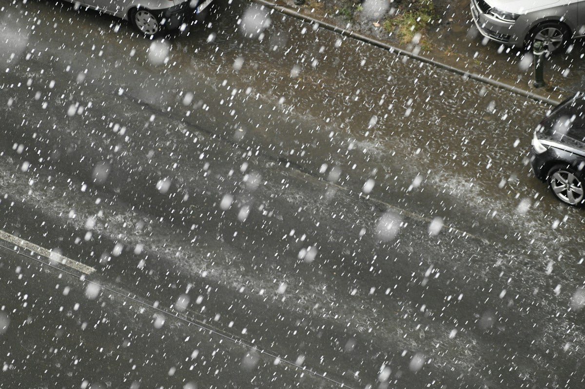 Hagel valt met kracht op een straat waar auto's geparkeerd staan